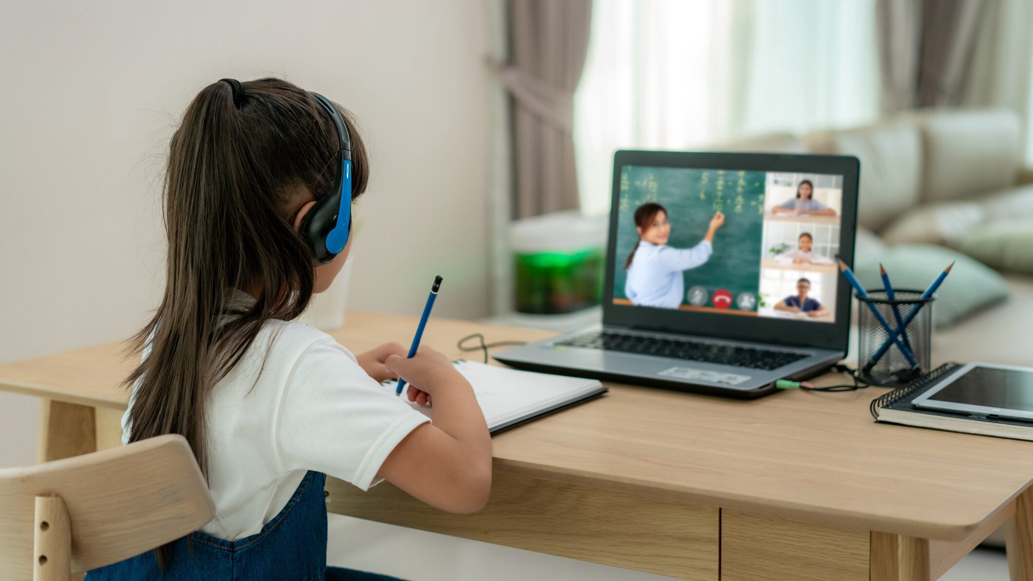 Asian girl student video conference e-learning with teacher and classmates on computer in living room at home. Homeschooling and distance learning ,online ,education and internet.